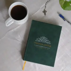 Vocatia Divina planner on table next to coffee, plant and rosary